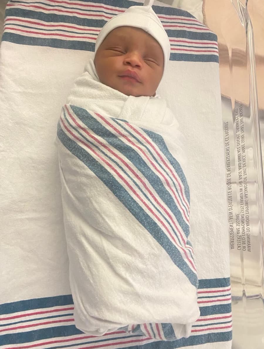 A newborn swaddled in a striped hospital blanket