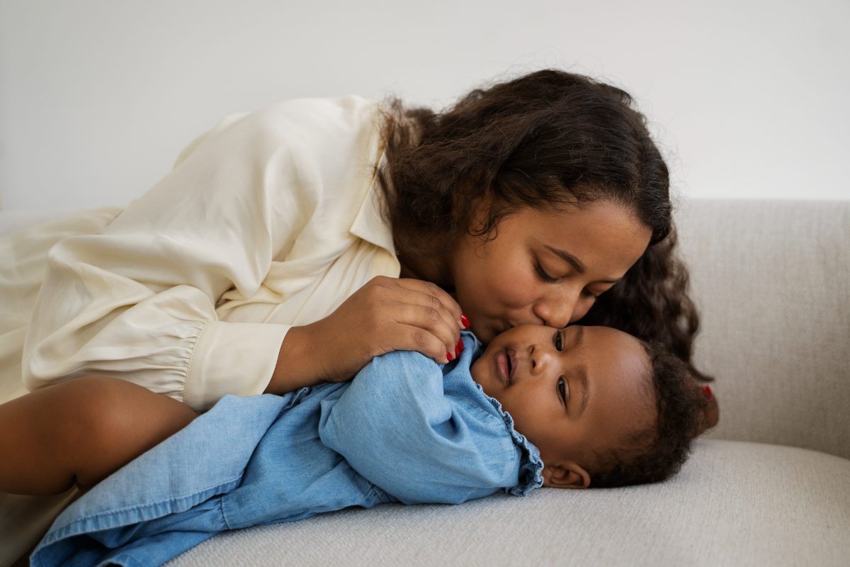 A mother holding and kissing her baby at home